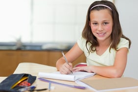 Smiling girl doing her homework in the kitchen