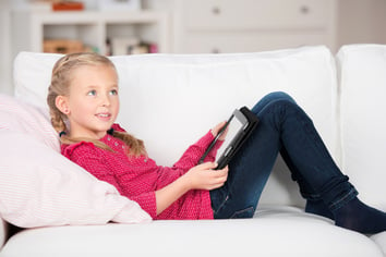 modern kid with digital pad lying on sofa